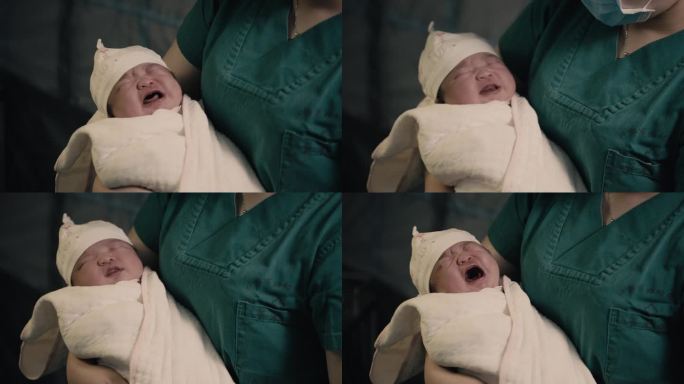 被医生抱在怀中哭泣的新生婴儿