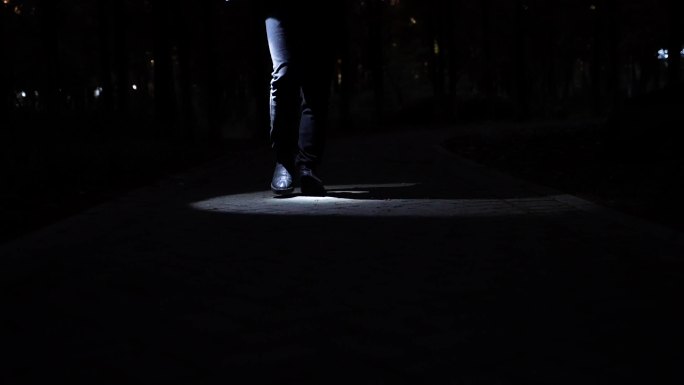 黑暗里前行的脚步特写打着光走路照亮前行路