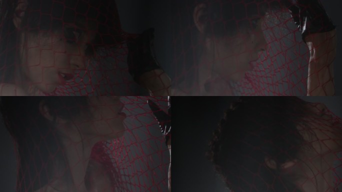 性感的黑发时尚模特被困在红色网中，露出面部表情。时尚视频。