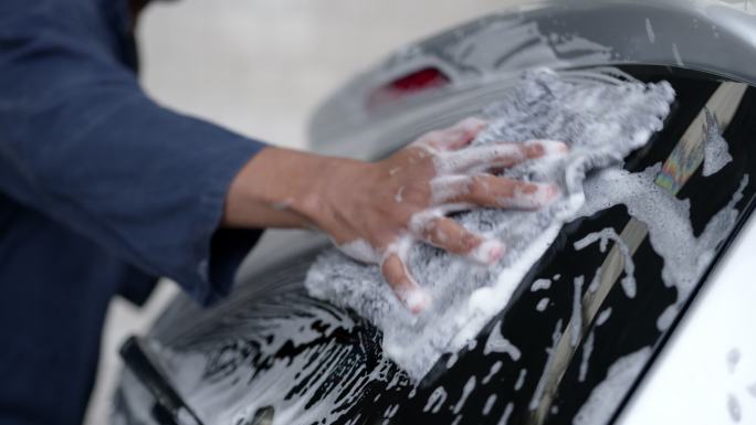 无法辨认的黑人工人在洗车场用海绵和肥皂清洗车窗