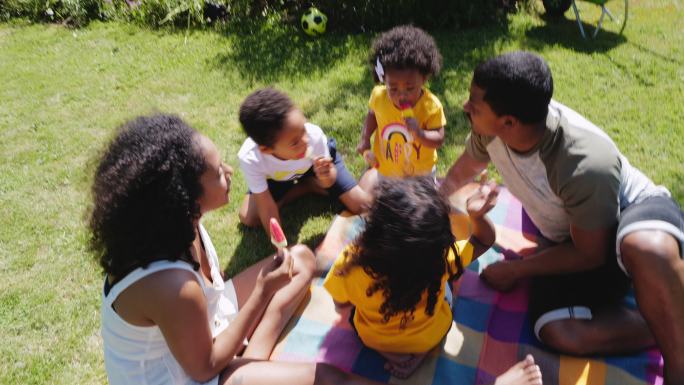 一家人在阳光明媚的夏日庭院里享用西瓜冰棍