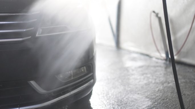 男性使用高压水喷雾清洁汽车