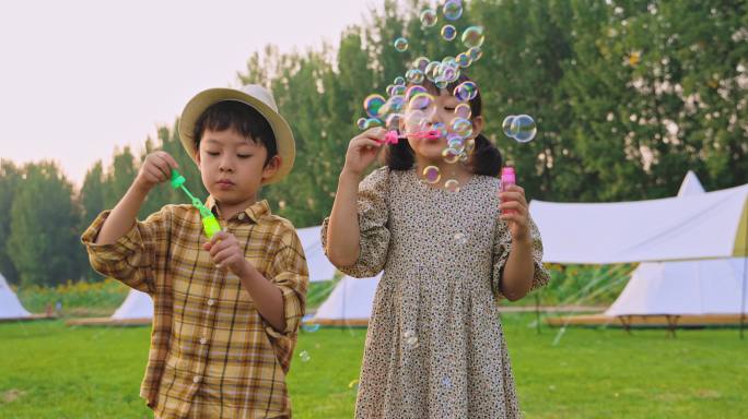 两个小孩在草地上吹泡泡