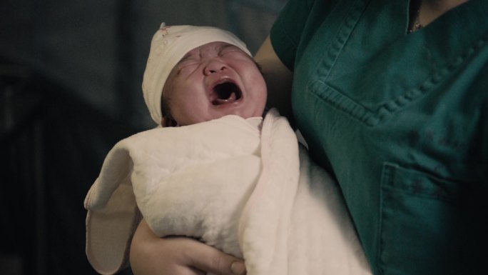 被医生抱在怀中哭泣的新生婴儿
