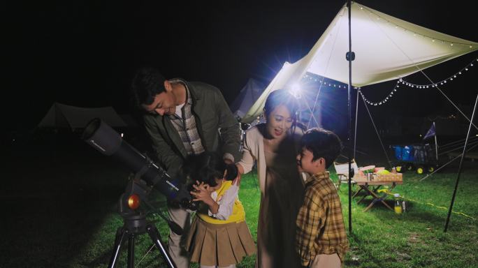 傍晚一家人在露营地用望远镜看星空