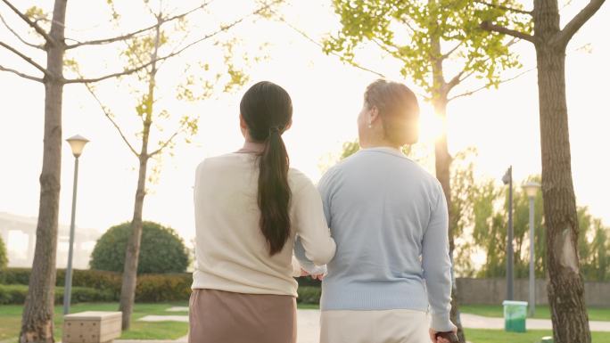 女儿陪伴母亲公园散步背影