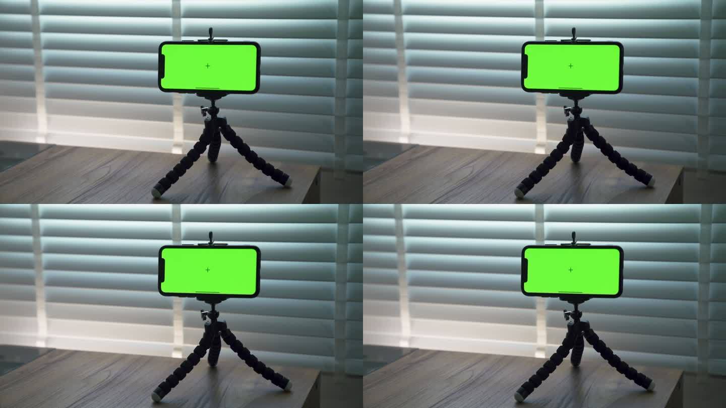 手机的绿色屏幕放在家里的支架上。