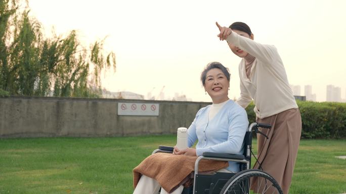 年轻女性陪伴坐轮椅的母亲公园散步