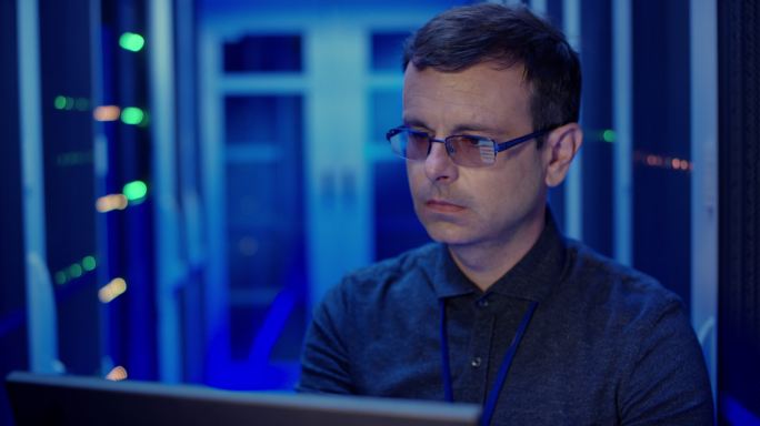 DS男计算机工程师在服务器室使用笔记本电脑评估服务器功能