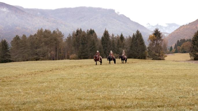三个人骑马在山间草地上