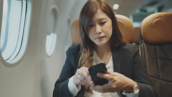 女商人在飞机上使用电话。