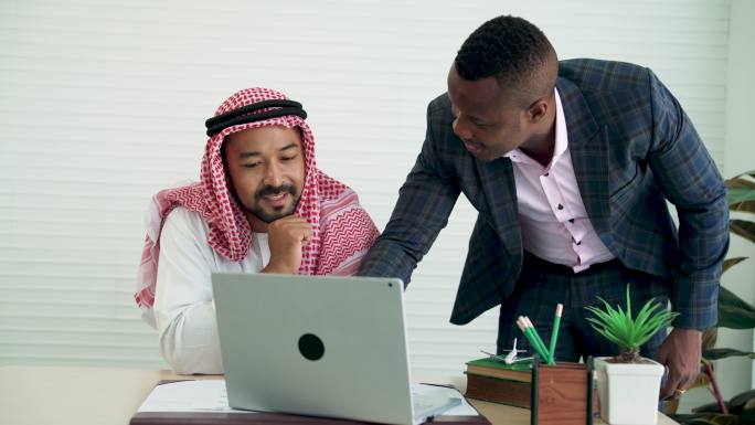 中东商人和非洲商人在办公室开会并使用笔记本电脑。