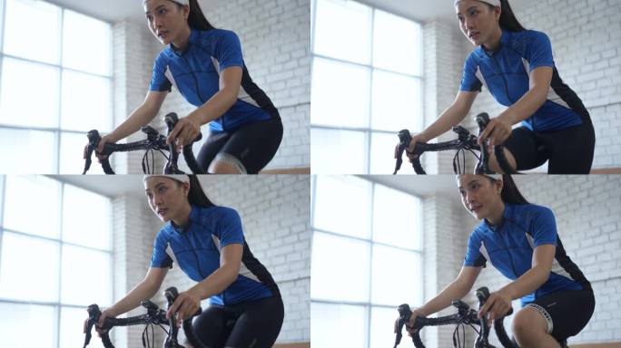 亚洲女子自行车运动员。她在家里锻炼。骑在教练车上