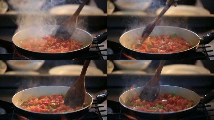 在平底锅中煎番茄和辣椒，准备食物，用搅拌勺搅拌食物