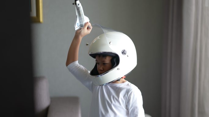 一个亚洲男孩玩着游戏，用地球仪和宇宙飞船假装宇航员。梦想未来和灵感的概念