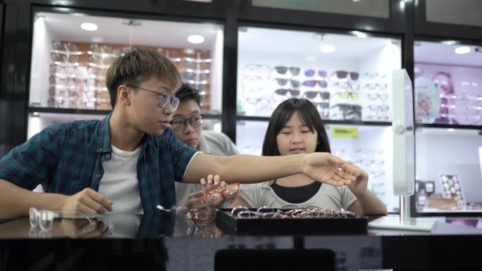 亚洲中国兄弟姐妹在眼镜店的镜子前试眼镜