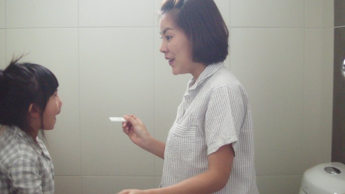 一位亚洲妇女正在检查怀孕测试。