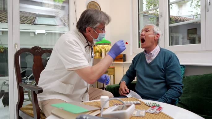 一名成年医生从一名患病患者身上采集口腔样本