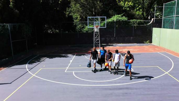 一群人走过篮球场的头顶。年轻人从上面玩体育