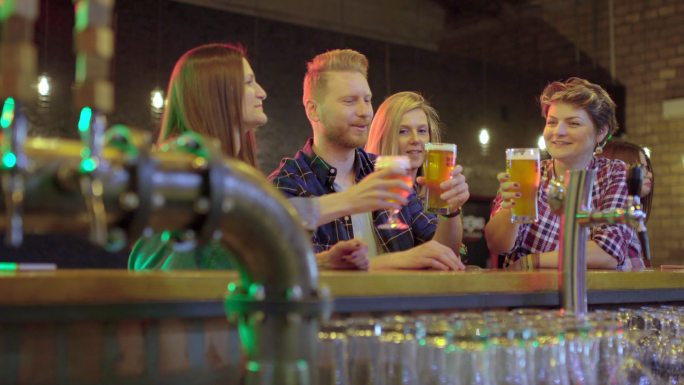 一群快乐的朋友在夜总会的酒吧边喝生啤