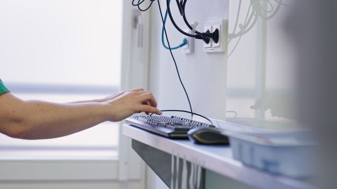 一位女外科医生在手术室用电脑键盘打字的特写镜头