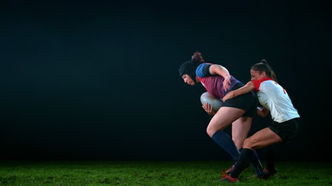 SLO MO LD女橄榄球运动员抓住对手的腰部，试图阻止她