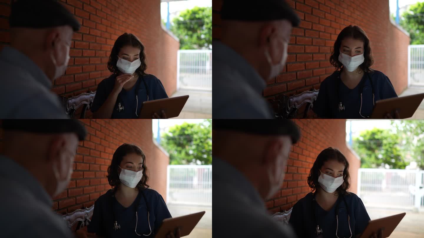 护士在家里与一位老年患者交谈-戴着口罩