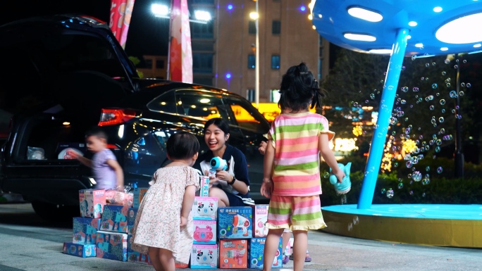 晚上广场公园和小朋友开心玩泡泡机美女摆摊