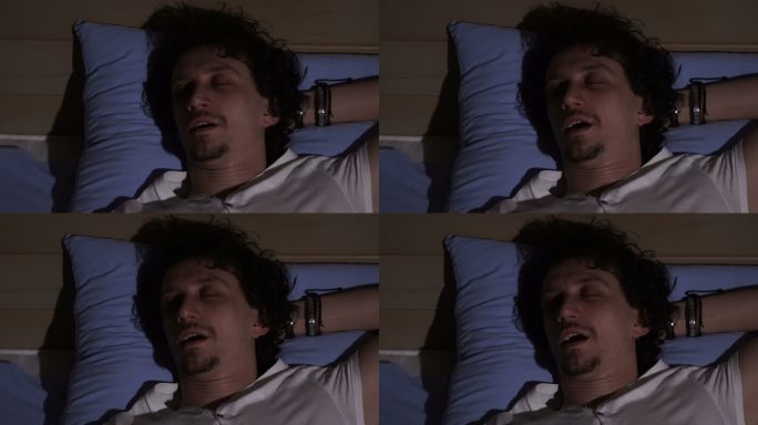 一个睡在床上打鼾的男人，特写镜头