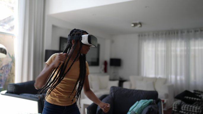 青少年女孩在家中使用VR眼镜玩耍