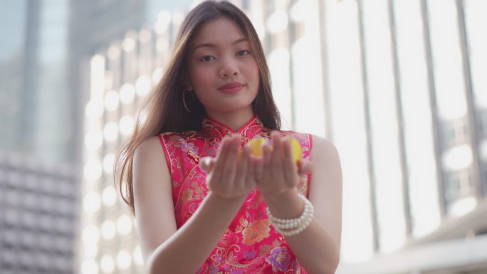 一位年轻的中国女子将黄金交给相机，祝她新年快乐，富有而幸运。