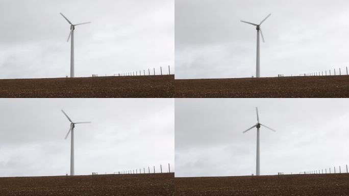 风力涡轮机在阴暗灰暗的耕地中转动