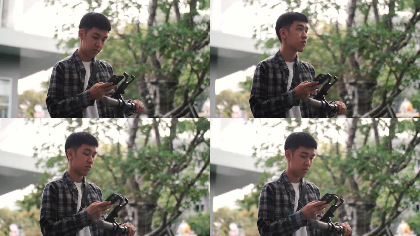一名手持智能手机的亚洲男子在电动滑板车上扫描二维码，开始上班以减少污染。