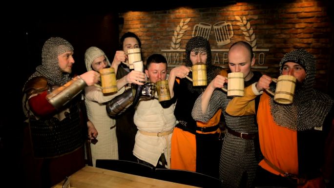 中世纪骑士在黑暗背景下喝啤酒