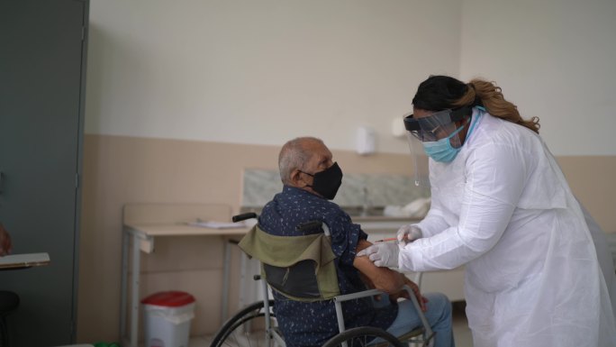 医生为轮椅上的老人接种疫苗-戴口罩