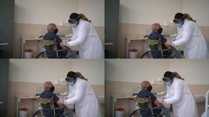 医生为轮椅上的老人接种疫苗-戴口罩