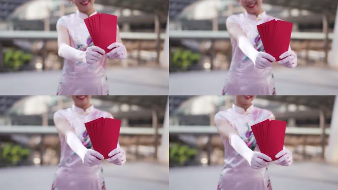 中国一名年轻女子将旗袍信封交给相机，祝她新年快乐，富贵吉祥。