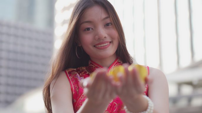 一位年轻的中国女子将黄金交给相机，祝她新年快乐，富有而幸运。