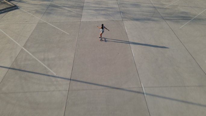 在美丽的夏日，亚洲女子在户外冲浪或滑板的鸟瞰图。早上，快乐的年轻女子在公园玩冲浪滑板。