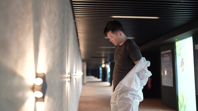 亚洲华人电影院卫生员摘下口罩防护工作服消毒后在电影院走道进行消毒