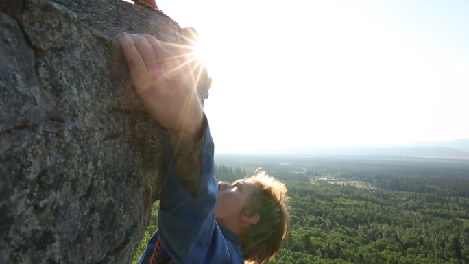 日出时，男性攀岩者登上垂直岩石