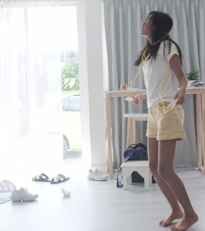 亚洲女孩在家里靠窗跳长袍，居家锻炼生活方式理念。