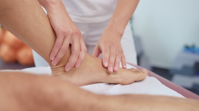 SLO MO女性运动按摩治疗师按摩患者脚踝有问题的区域