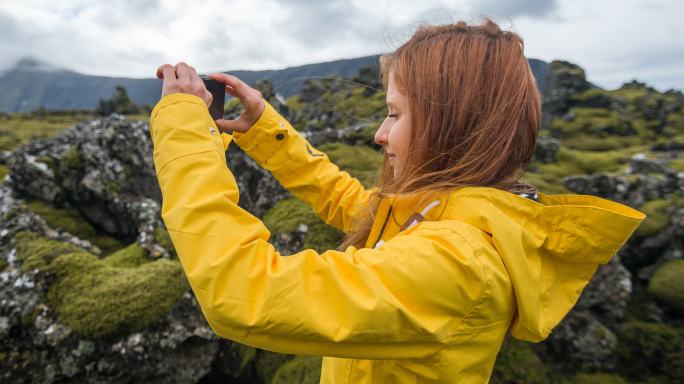 拍摄苔藓覆盖的熔岩石照片的女人