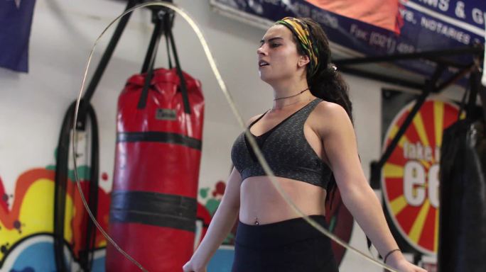一名年轻女子在拳击馆用跳绳热身。