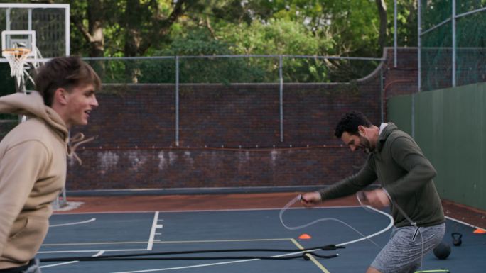 父亲和儿子在篮球比赛中使用跳绳。年轻人和十几岁的男孩用跳绳热身
