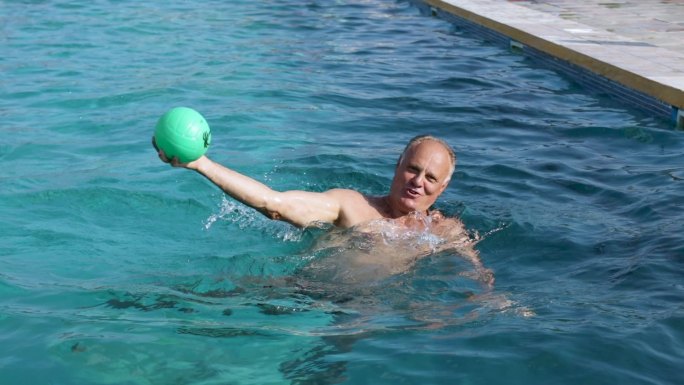 老年人在游泳池里打球。像职业水球运动员一样假装射门