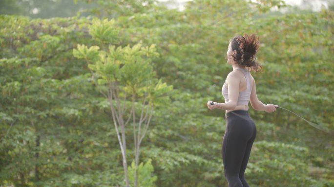亚洲女性用跳绳练习有氧运动以减肥的场景。
