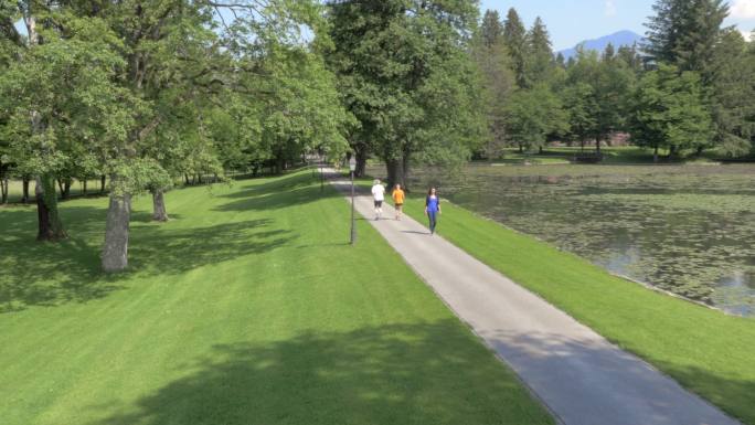 AERIAL男女跑步者在阳光下穿过公园