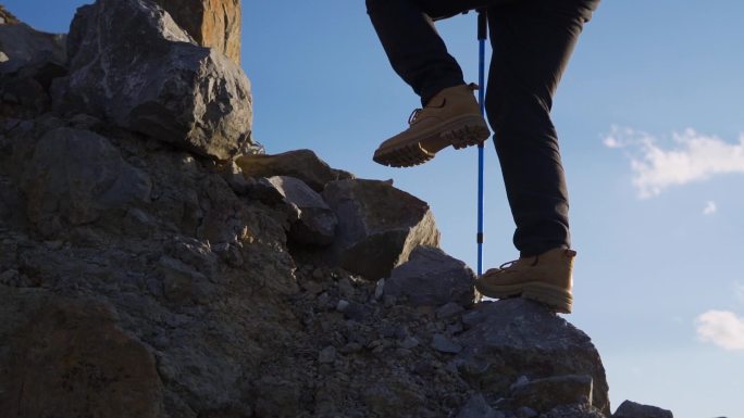 登山脚步特写踩着石头登山户外探险旅行者